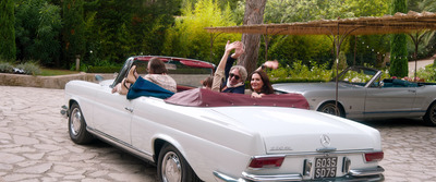 a group of people riding in the back of a white car