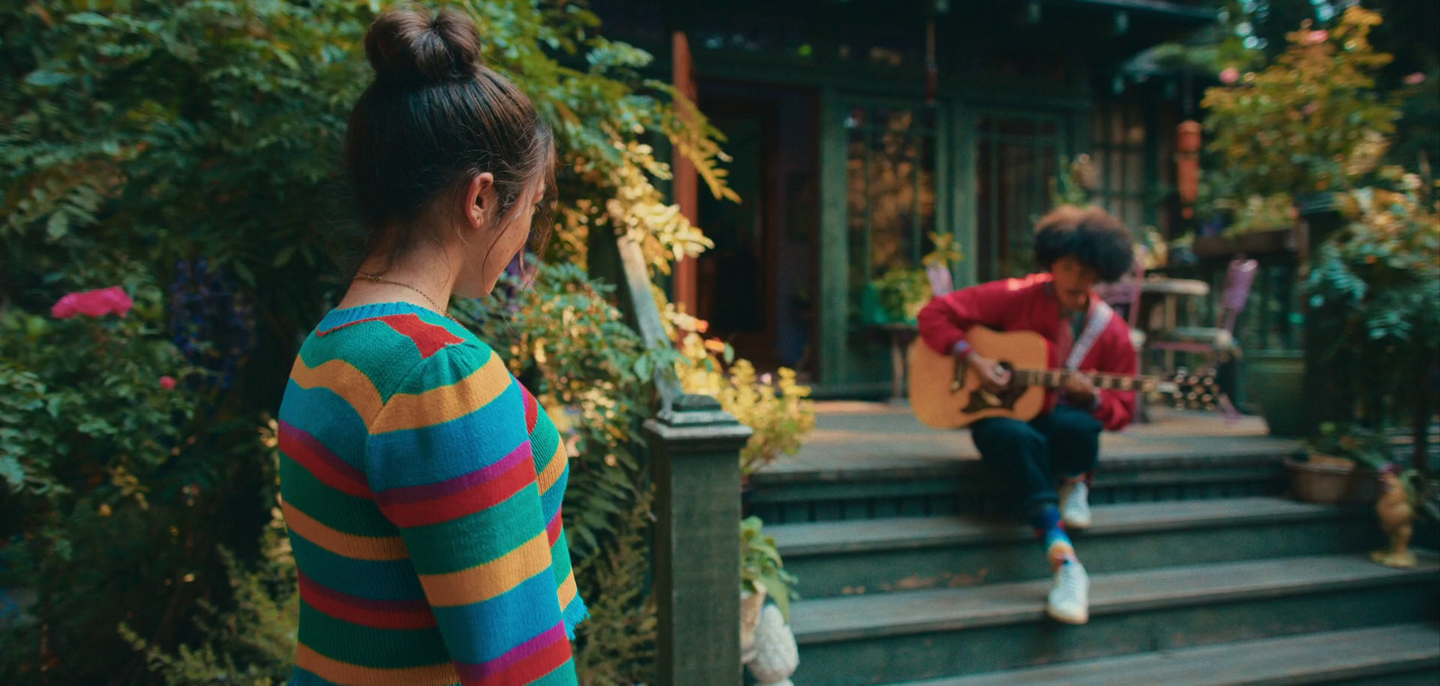 a woman sitting on a porch playing a guitar