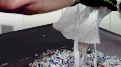 a person pours a bag of shredded paper into a sink