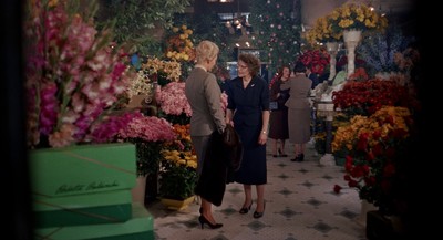 a couple of women standing next to each other in a room filled with flowers