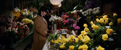 a couple of men standing next to a bunch of flowers