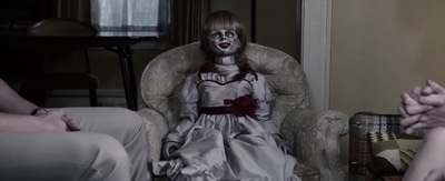 a creepy doll sitting in a chair in a living room