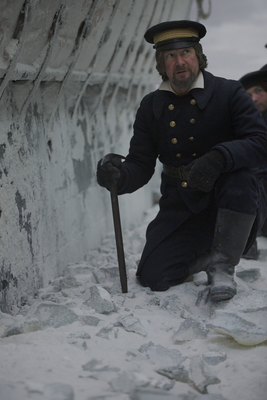 a man kneeling down in the snow with a cane