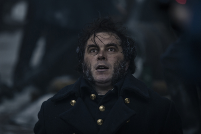 a man in a black coat with a surprised look on his face