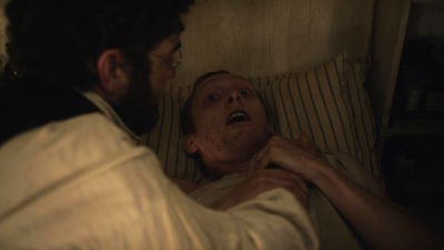 a man laying in bed with another man looking at him