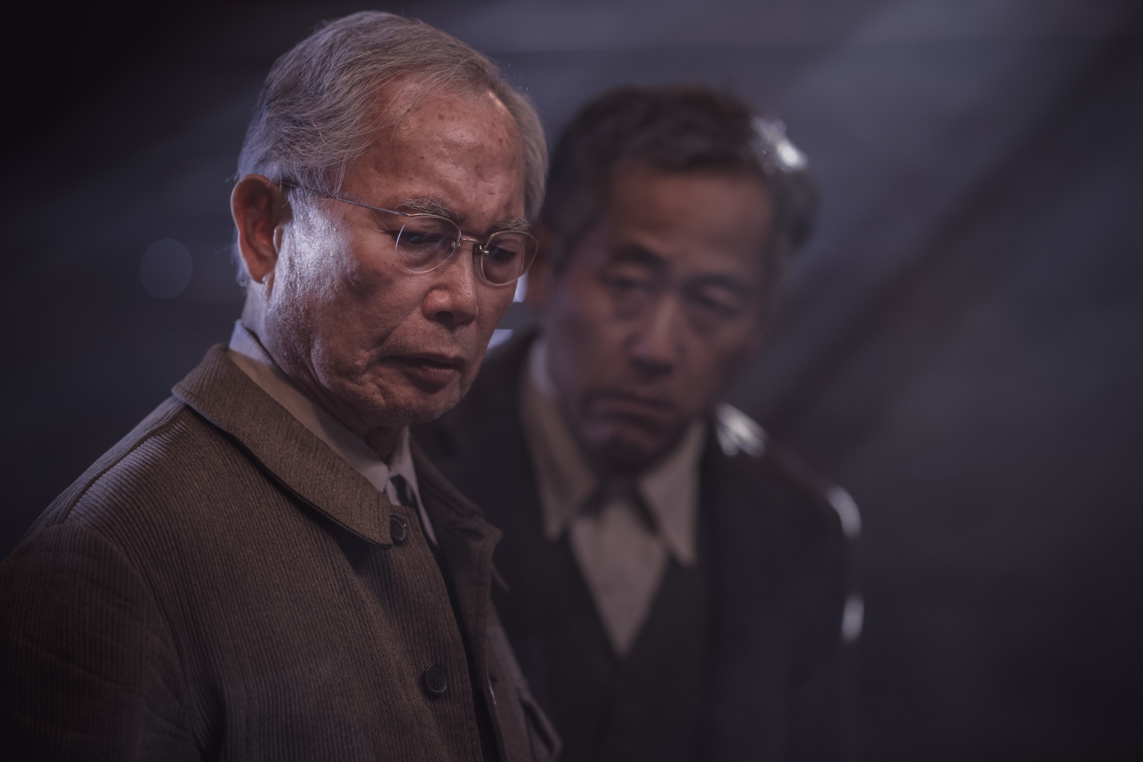 two men standing next to each other in a dark room