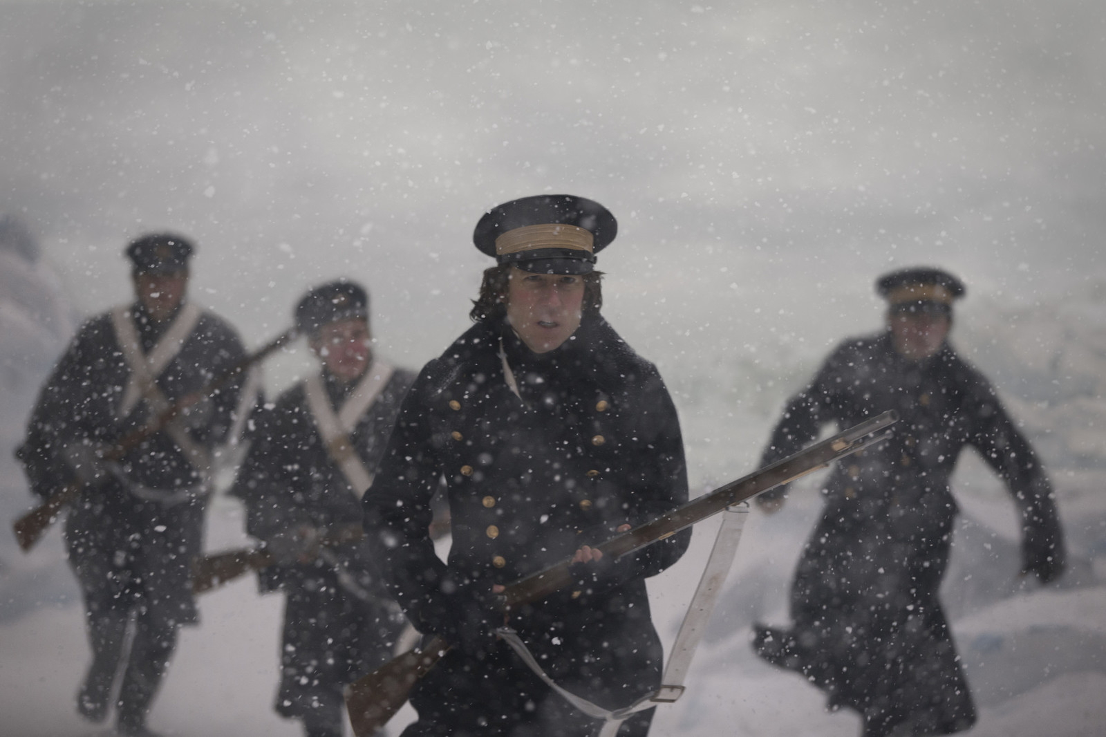 a group of men in uniforms walking through the snow