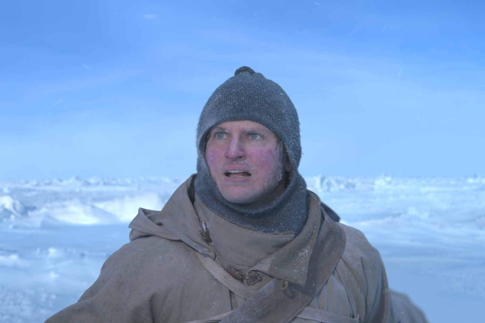 a man wearing a hat and scarf standing in the snow