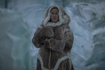 a woman in a fur coat standing in front of a glacier