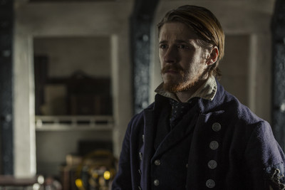 a man with long hair and a beard standing in a room