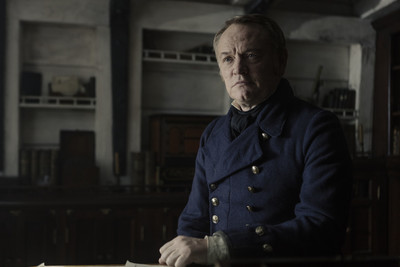 a man in a blue coat sitting at a table