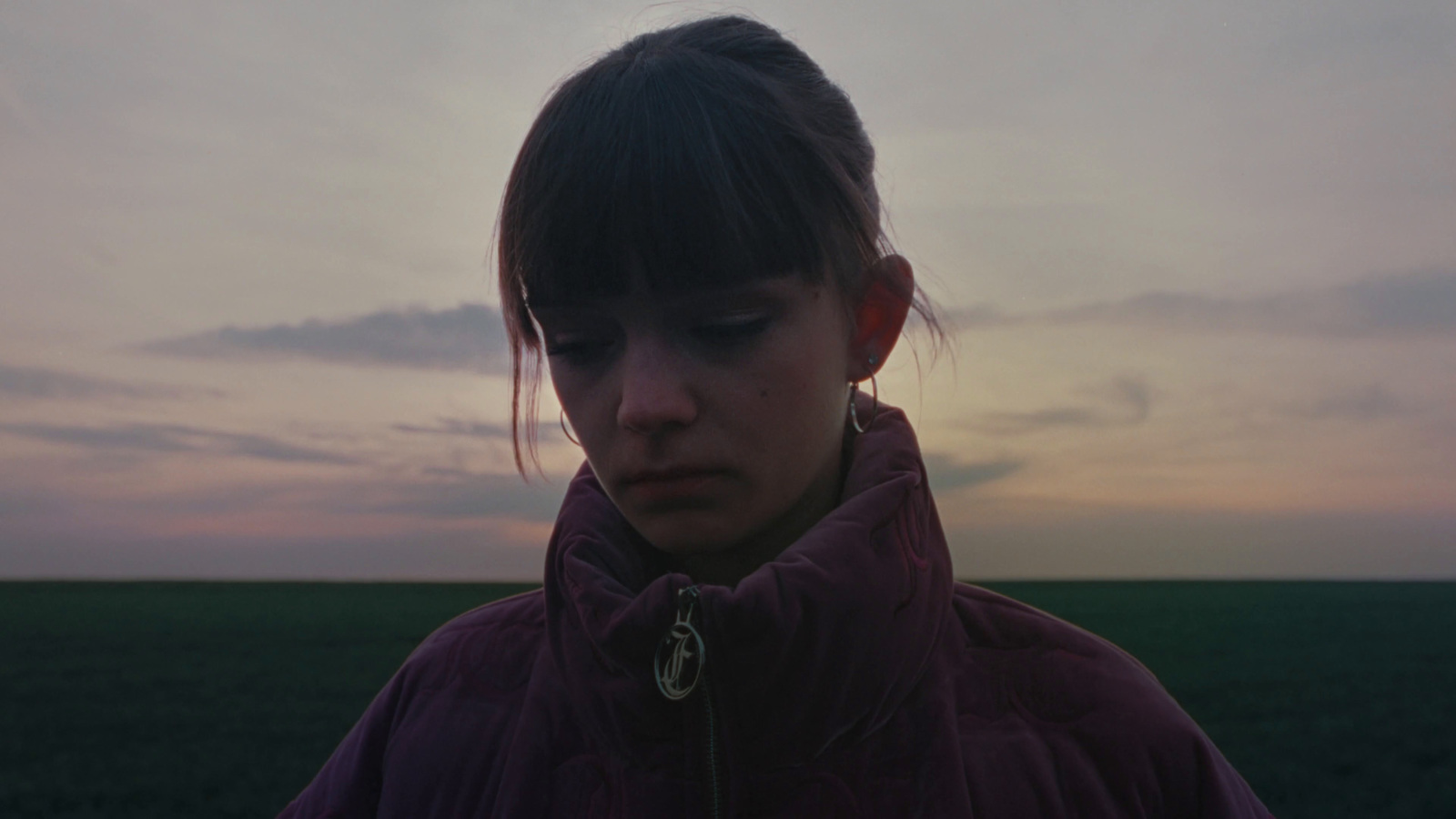 a woman in a purple jacket standing in a field