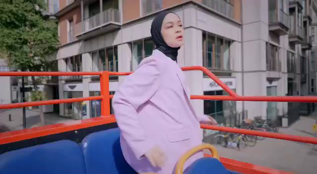 a woman in a hijab is standing on a bus