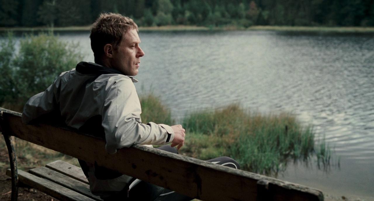 a man sitting on a bench next to a lake