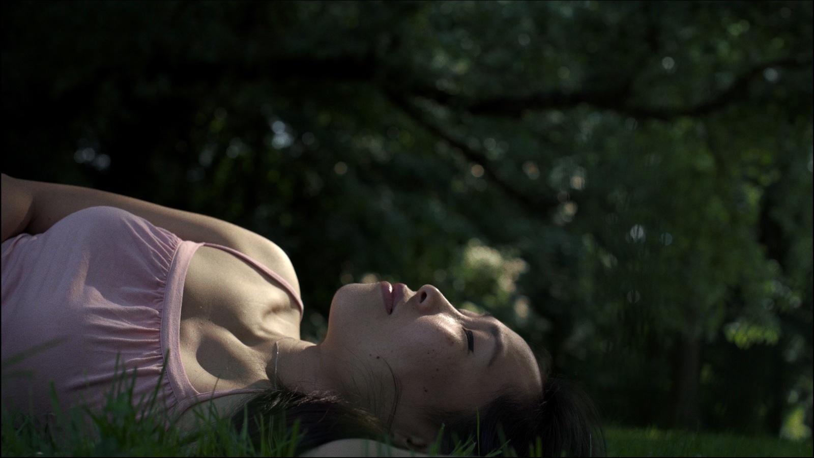 a woman laying in the grass with her eyes closed