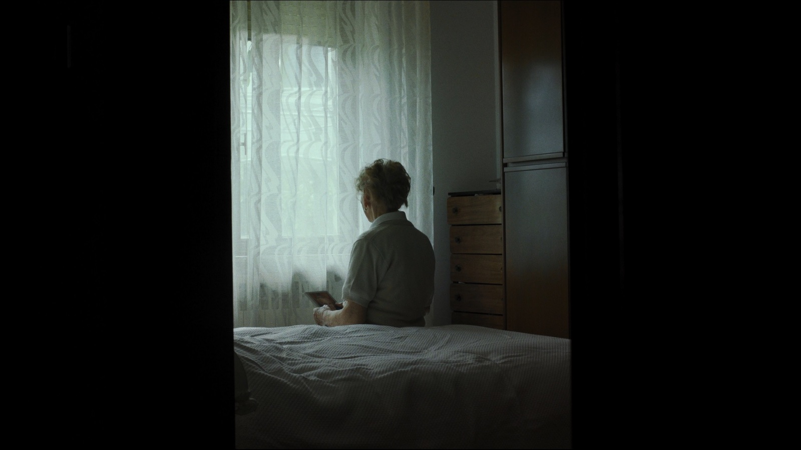 a woman sitting on a bed looking out a window