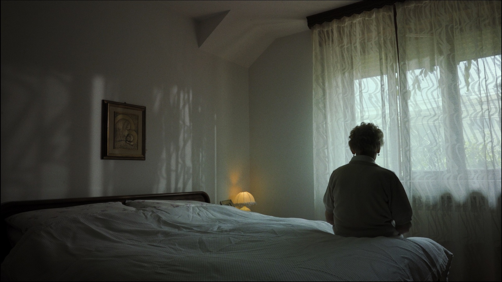 a person sitting on a bed looking out a window