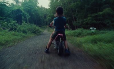 a young boy riding a small motorcycle down a dirt road