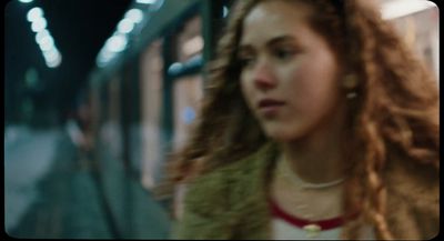 a woman with long hair standing next to a train