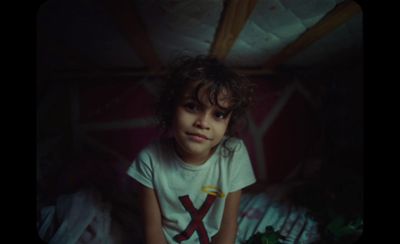 a young girl sitting on a bed in a dark room