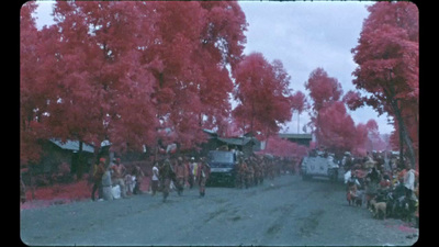 a group of people walking down a street next to trees