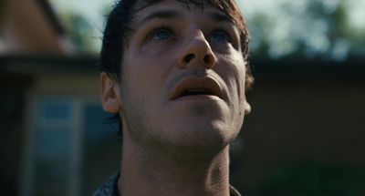 a man looking up into the sky with a house in the background