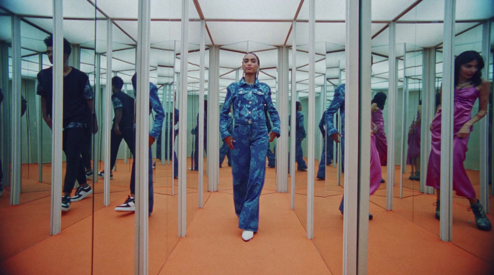 a man in a blue suit walking through a room filled with mirrors