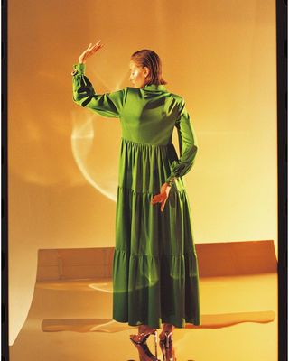 a woman in a green dress standing in front of a wall