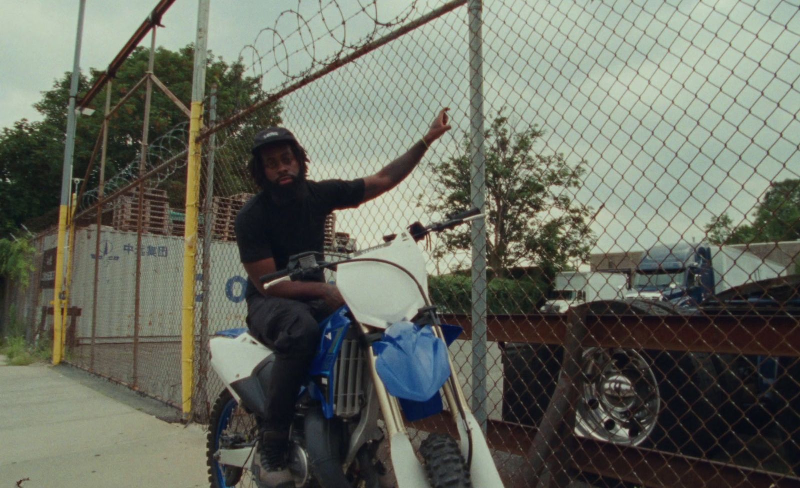 a man sitting on a dirt bike next to a fence