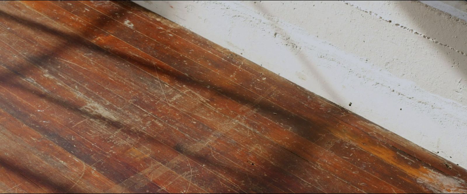 a wooden floor with a white wall in the background