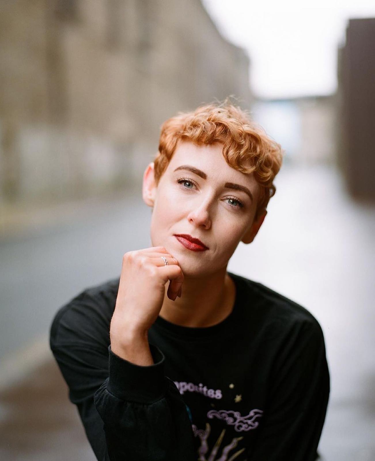 a woman with red hair and a black shirt