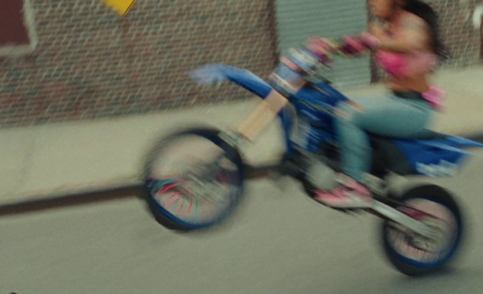 a girl is riding a small blue motorcycle