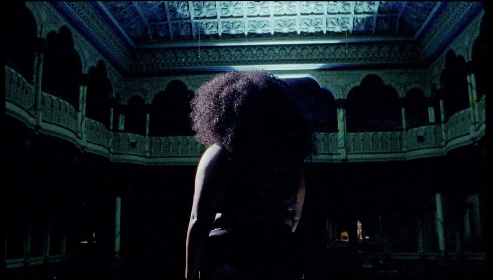 a woman standing in a dark room with a ceiling