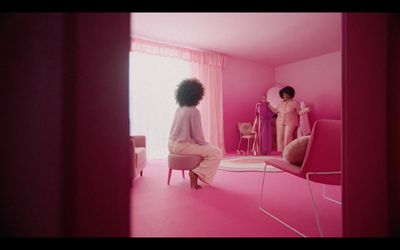 a woman sitting on a chair in a pink room