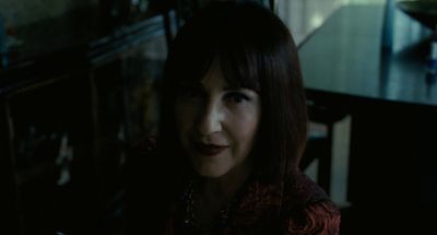 a woman sitting in a dark room looking at the camera