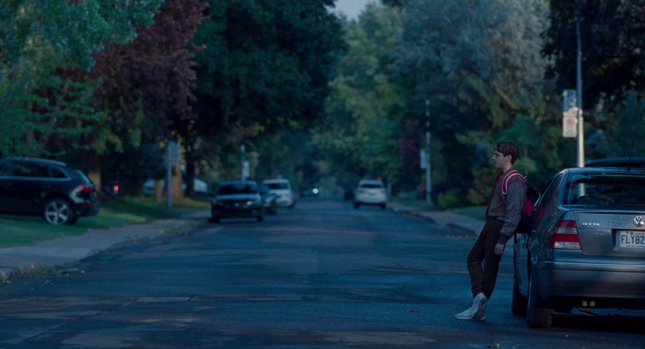 a man standing next to a parked car on a street