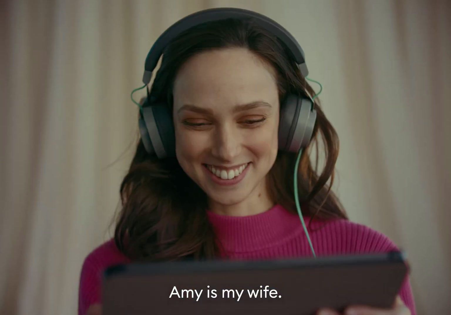 a woman wearing headphones and looking at a tablet