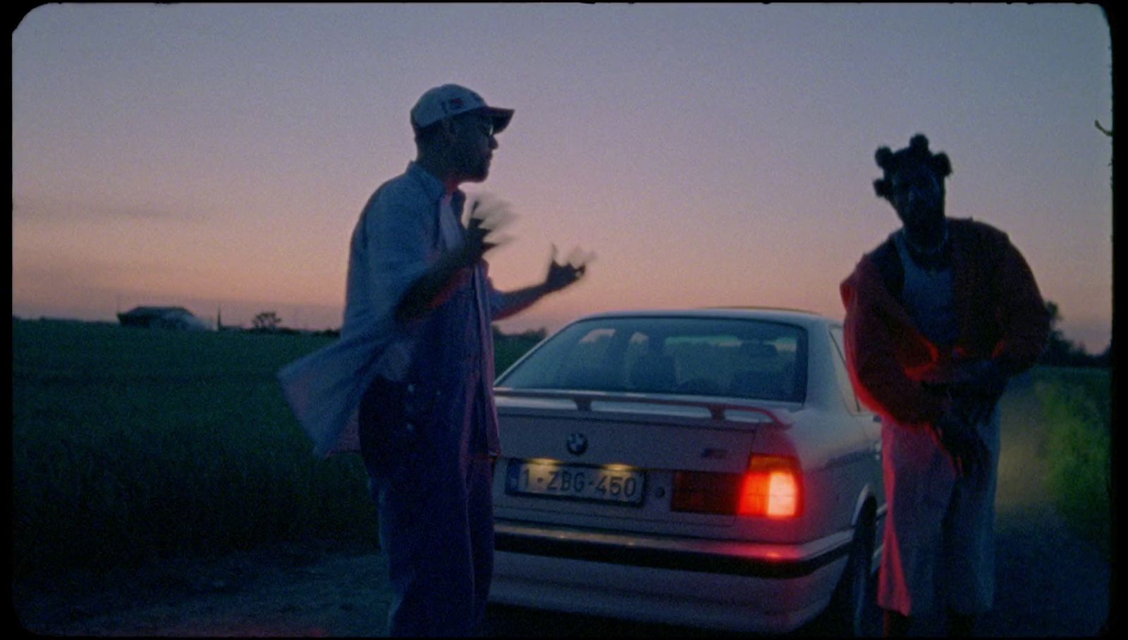 a couple of men standing next to a white car