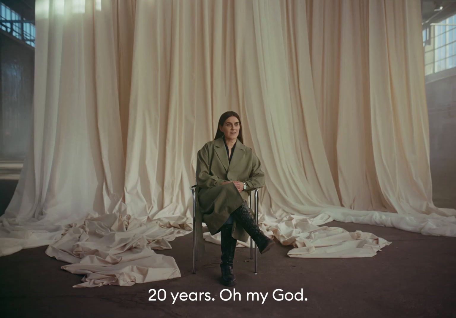 a woman sitting in a chair in front of a curtain