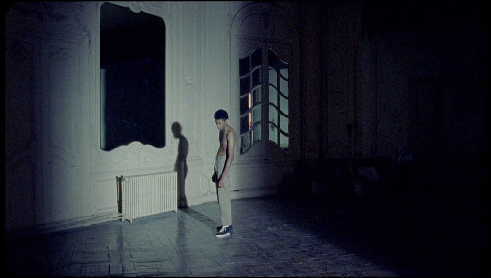 a man standing in a dark room next to a mirror