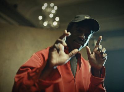 a man in a red shirt and hat making a peace sign