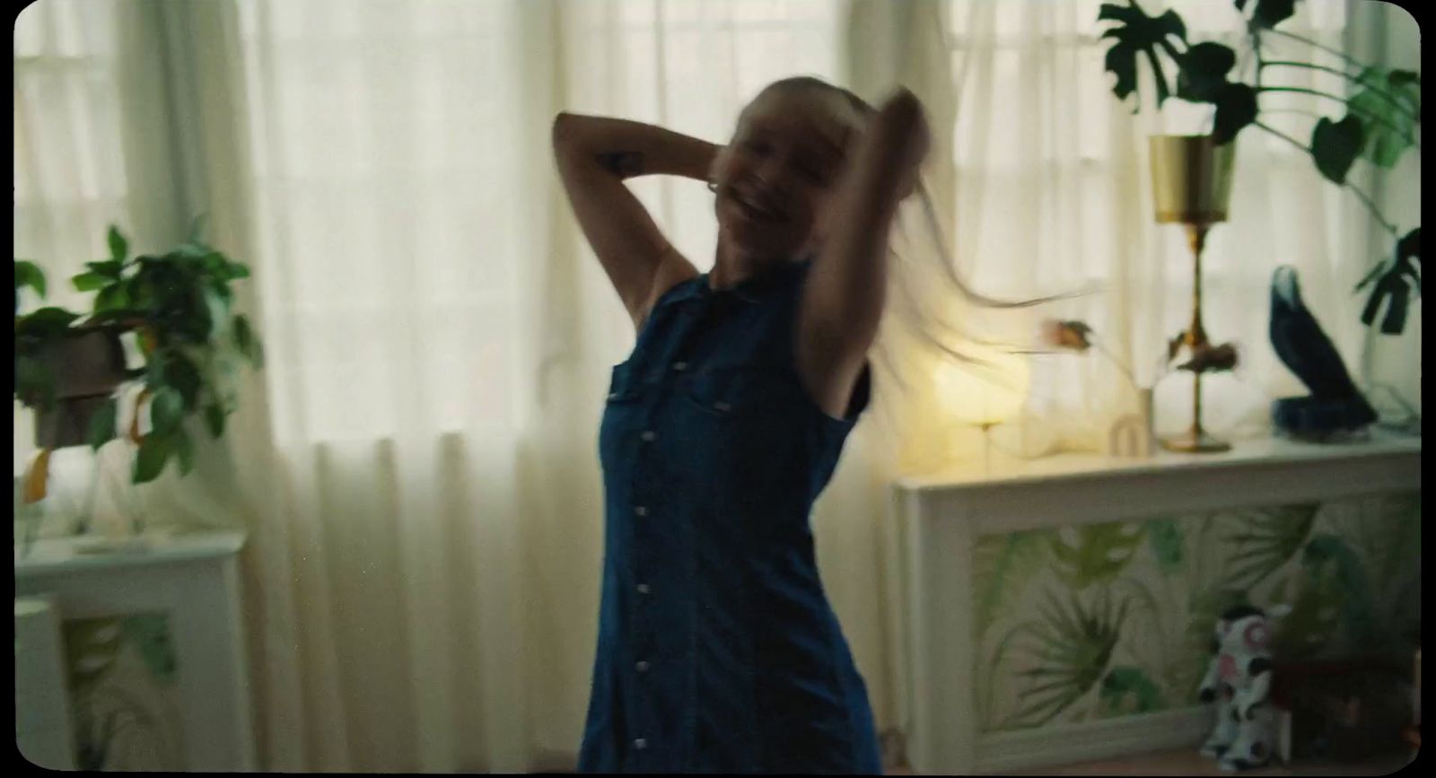 a woman in a blue dress dancing in a living room