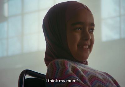 a young girl in a wheelchair smiling at the camera