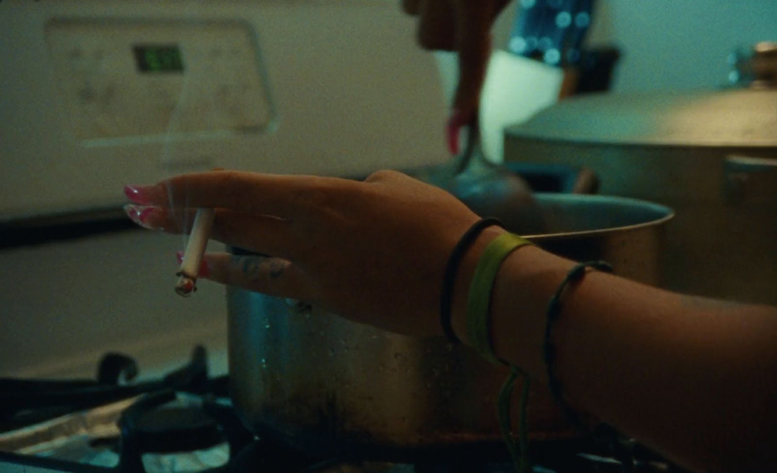 a woman is holding a spoon over a pot on the stove