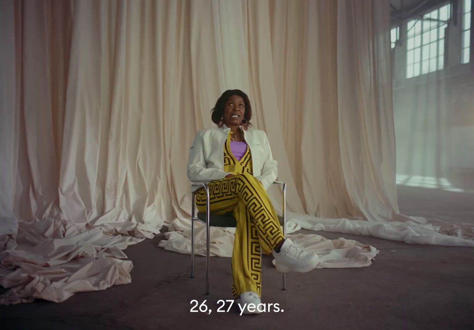 a woman sitting on a chair in front of a curtain