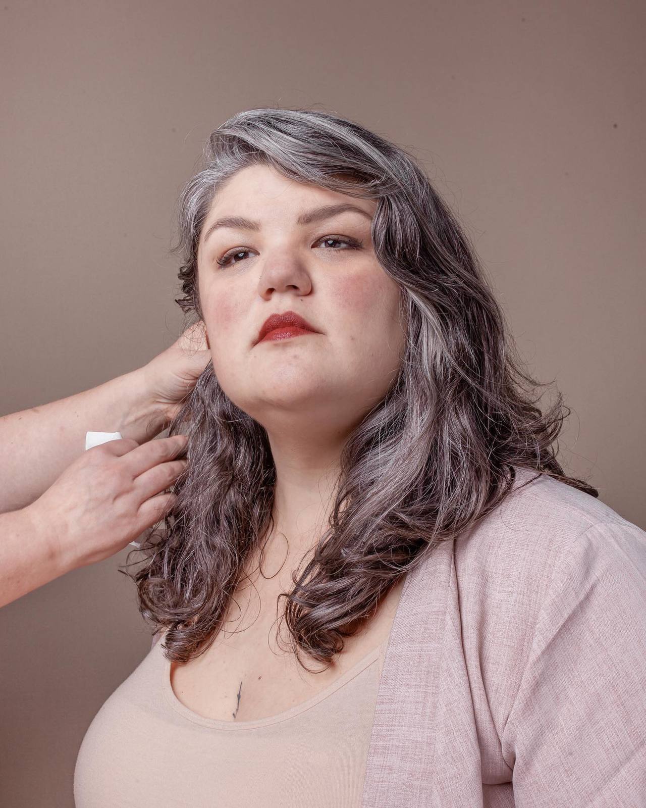 a woman getting her hair styled by a woman with grey hair