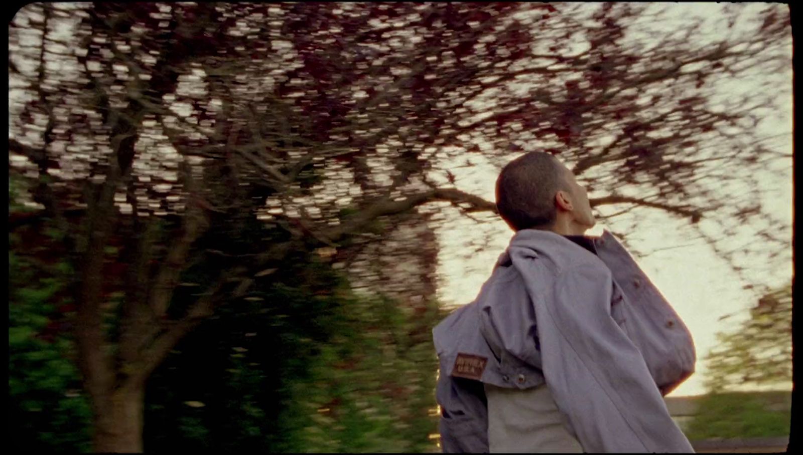 a man walking down a street next to a tree