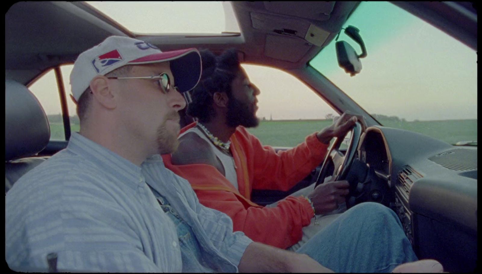 a man driving a car with another man behind him