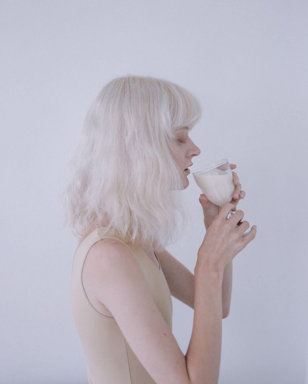 a woman with white hair holding a glass of milk