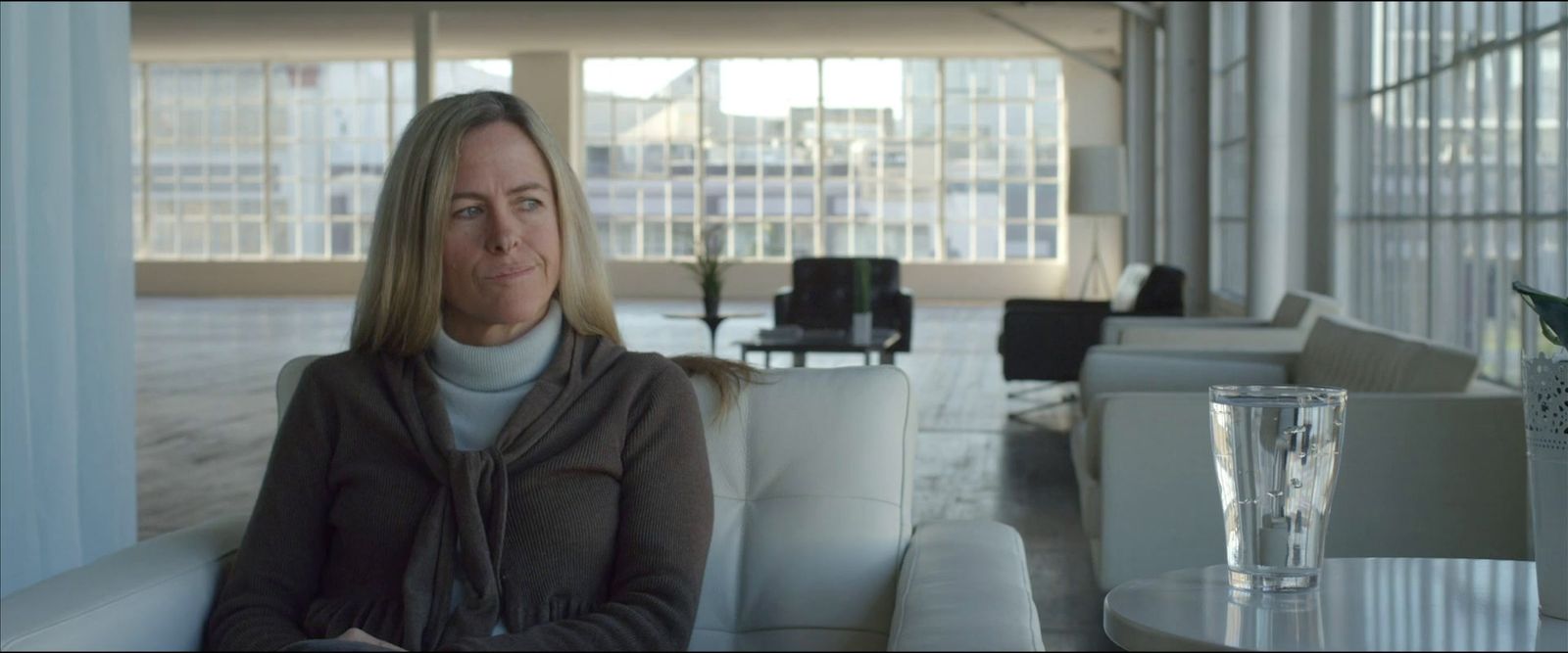 a woman sitting on a couch next to a glass of water